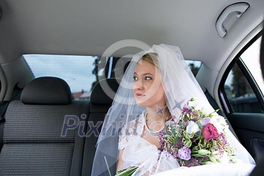 Portrait of a beautiful young bride waiting in the car on her way to the wedding ceremony