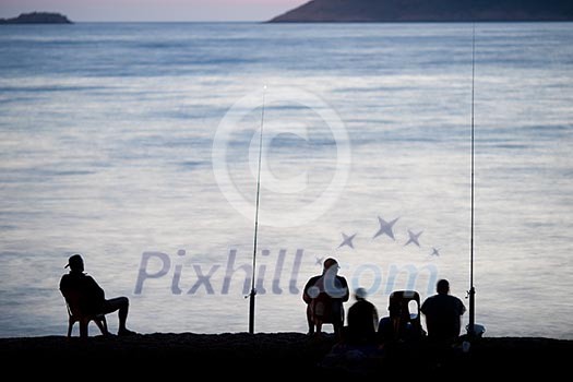 Sea/Ocean fishing - fishermen sitting by the sea/ocean in darkness waiting for the catch Sea/Ocean fishing - fishermen sitting by the sea/ocean in darkness waiting for the catch