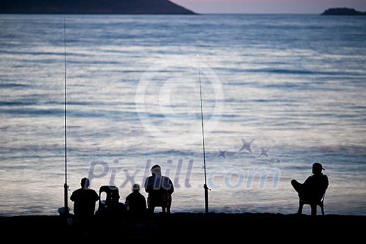 Sea/Ocean fishing - fishermen sitting by the sea/ocean in darkness waiting for the catch Sea/Ocean fishing - fishermen sitting by the sea/ocean in darkness waiting for the catch