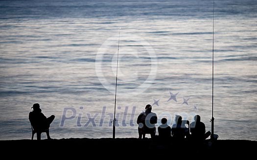 Sea/Ocean fishing - fishermen sitting by the sea/ocean in darkness waiting for the catch