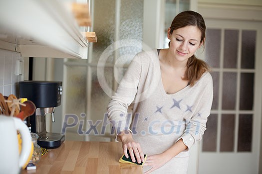 Young woman doing housework, cleaning the kitchen