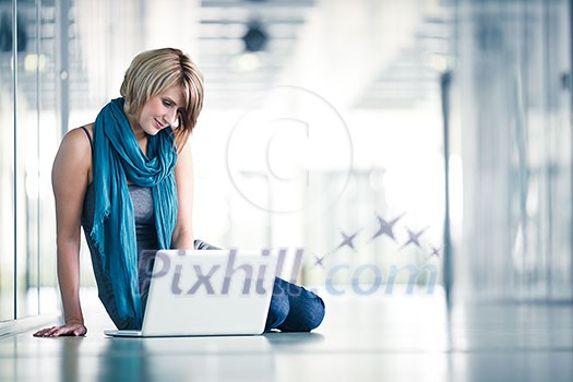 Pretty young female student with a laptop computer on college/university campus (shallow DOF; color toned image)