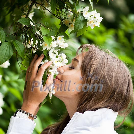 Beautiful young woman smelling white jasmin flowers Beautiful young woman smelling white jasmin flowers