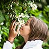 Beautiful young woman smelling white jasmin flowers