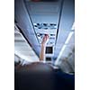 Passenger adjusting air conditioning above his seat while on board of an aircraft