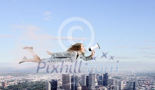 Young pretty businesswoman flying in blue sky sreaming in megaphone