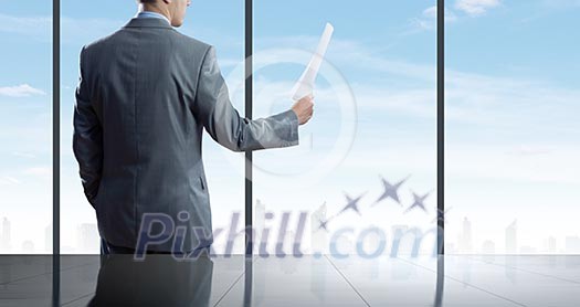 Businessman standing against office window reading documents