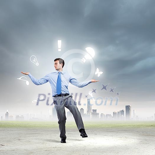 Young businessman juggling with conceptual symbols against city background Young businessman juggling with conceptual symbols against city background