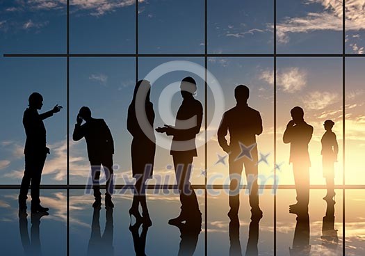 Silhouettes of businesspeople standing against panoramic office window