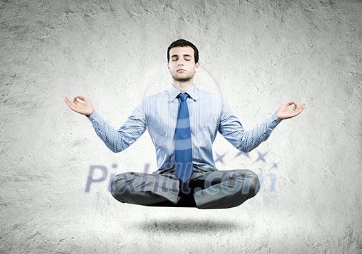 Young businessman sitting in lotus pose and meditating