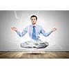 Young businessman sitting in lotus pose and meditating