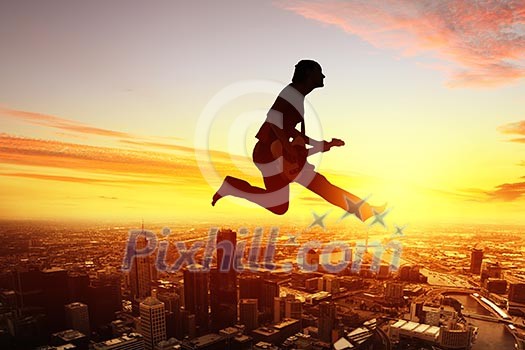 Silhouette of dancer jumping against city in lights of sunrise