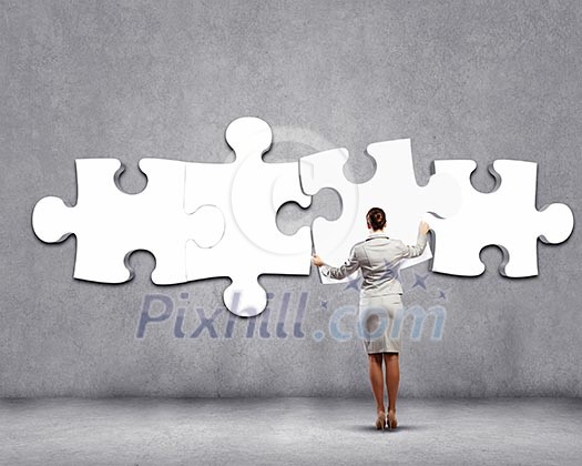 Rear view of businesswoman connecting white puzzle