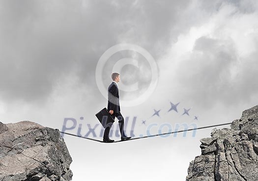 Conceptual image of businessman walking on rope above gap Conceptual image of businessman walking on rope above gap