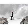 Conceptual image of businessman walking on rope above gap