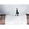 Conceptual image of businessman walking on rope above gap