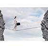 Young confident businesswoman walking on rope above gap