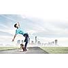 Skater in jeans riding on road against city background