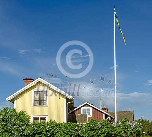 A yelow wooden house a flag pole and blue skies
