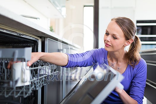 Housework: young woman putting dishes in the dishwasher