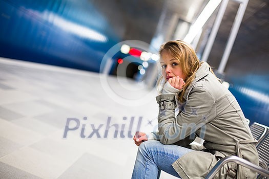 Sad and alone in a big city - Depressed young woman sitting in a metro station, feeling sorrow, regret