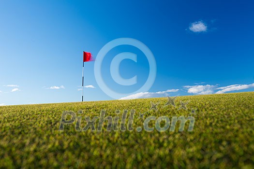 Red golf flag on a golf course, moving in the wind (motion blurred image); St. Andrews, Scotland