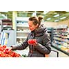 Beautiful, young woman shopping for fruits and vegetables in produce department of a grocery store/supermarket (shallow DOF; color toned image)