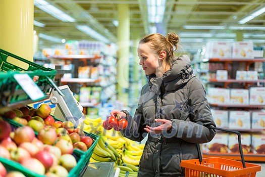 Beautiful, young woman shopping for fruits and vegetables in produce department of a grocery store/supermarket (shallow DOF; color toned image)