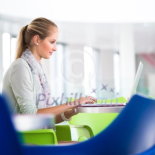 On campus - pretty, female student with books and laptop working while on a college/university campus (color toned image, shallow DOF)