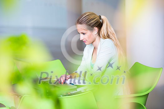 Student on campus - pretty, female student with books and laptop during her school day on campus school library (color toned image)