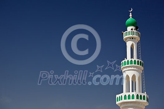 White mosque with minaret against blue sky (Sur, Oman)