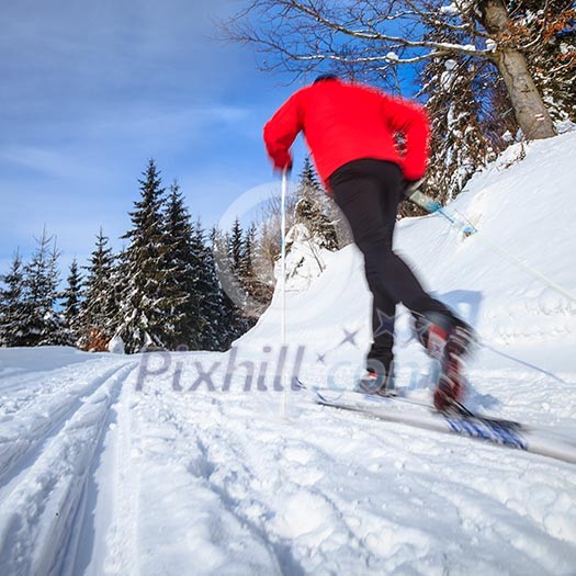 Cross-country skiing: young man cross-country skiing on a lovely sunny winter day (motion blur technique is used to convey movement)