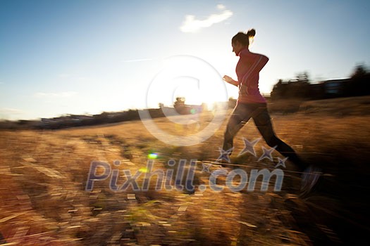 Young woman running outdoors on a lovely sunny winter/fall day (motion blurred image) Young woman running outdoors on a lovely sunny winter/fall day (motion blurred image)