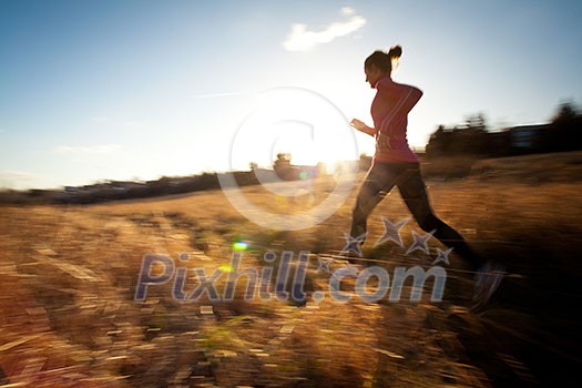 Young woman running outdoors on a lovely sunny winter/fall day (motion blurred image)