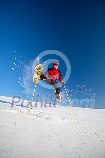 Young man showshoeing outdoors on a lovely snowy winter day (motion blurred image)