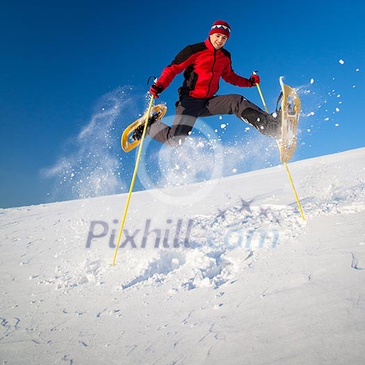 Young man having fun while snowshoeing outdoors on a lovely snowy winter day