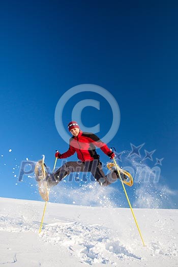 Young man having fun while snowshoeing outdoors on a lovely snowy winter day