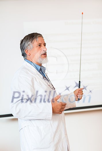 Senior chemistry professor giving a lecture in front of classroom full of students (shallow DOF; color toned image) Senior chemistry professor giving a lecture in front of classroom full of students (shallow DOF; color toned image)