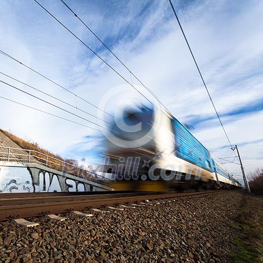 Fast train passing under a bridge on a lovely summer day (motion blurred image)