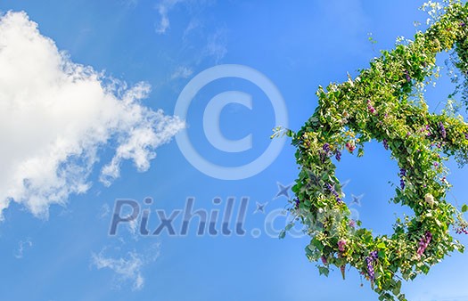 A swedish midsummers pole on a blue sky with clouds