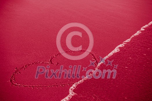 Concept of infidelity or fragile/fugitive/ephemeral love: heart drawn in sand being washed by the sea Concept of infidelity or fragile/fugitive/ephemeral love: heart drawn in sand being washed by the sea