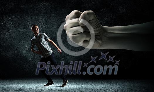 Funny image of young man trying to escape from huge hand