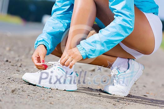 Young healthy girl tie shoelaces of sneakers