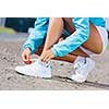 Young healthy girl tie shoelaces of sneakers