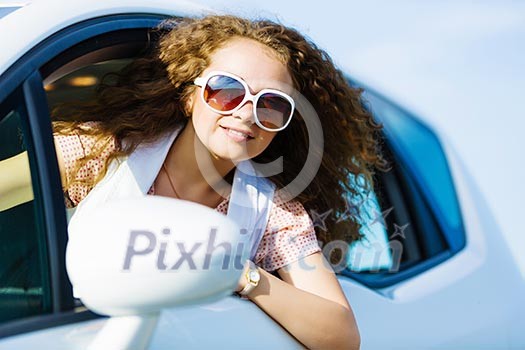 Young pretty woman driving car and leaning out of car window Young pretty woman driving car and leaning out of car window