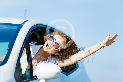 Young pretty woman driving car and leaning out of car window