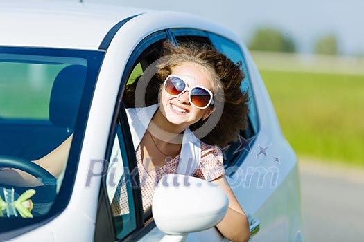 Young pretty woman driving car and leaning out of car window Young pretty woman driving car and leaning out of car window