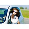 Young pretty woman driving car and leaning out of car window