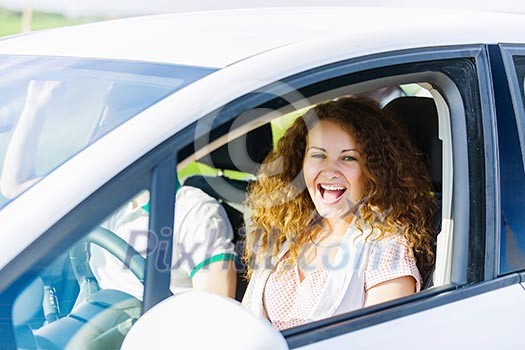 Young pretty woman driving car and leaning out of car window Young pretty woman driving car and leaning out of car window