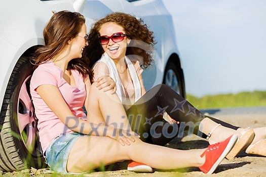 Young pretty women sitting near white car at side of road